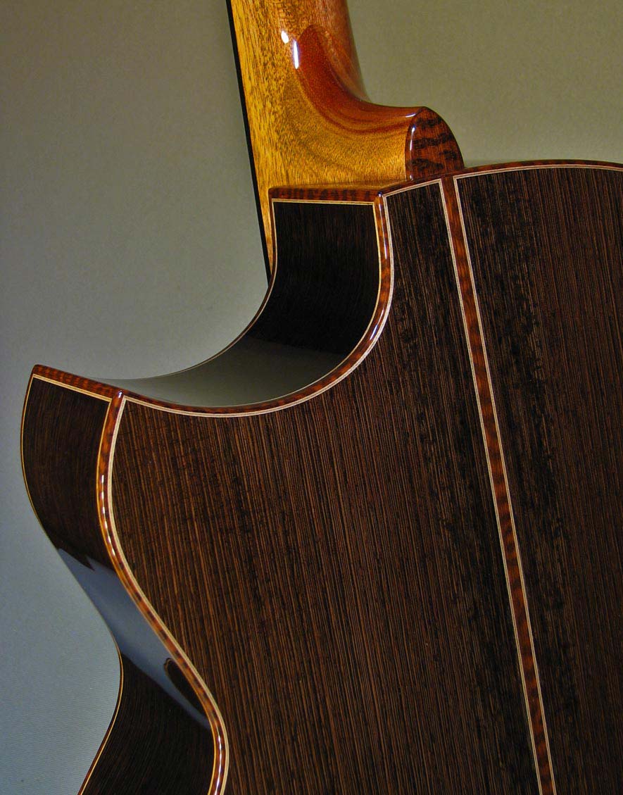 A close-up of a wenge guitar by Chasson Guitars, showing the hardwood’s dark brown and black grain.